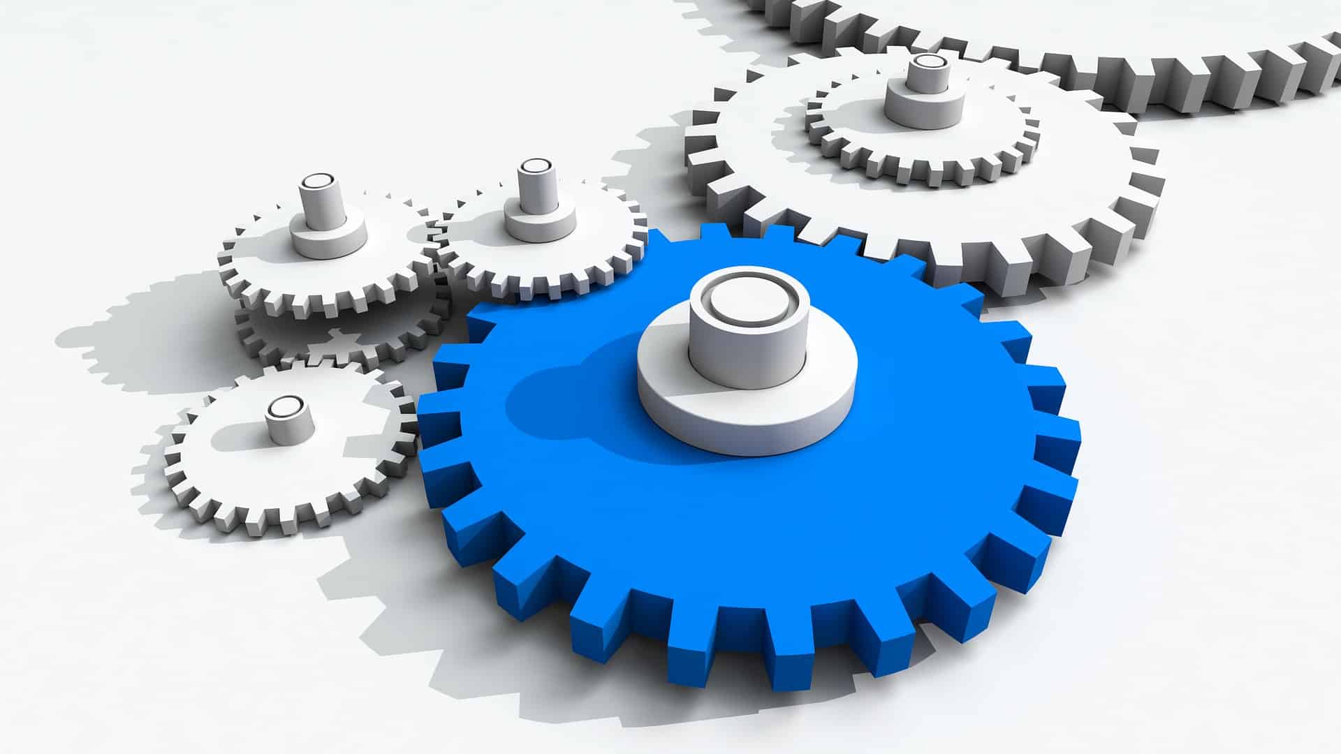 business systemization_interlocking parts 3D illustration of interlocking white gears driven by a large central blue gear, symbolizing business systemization, integrated business systems and operational efficiency.